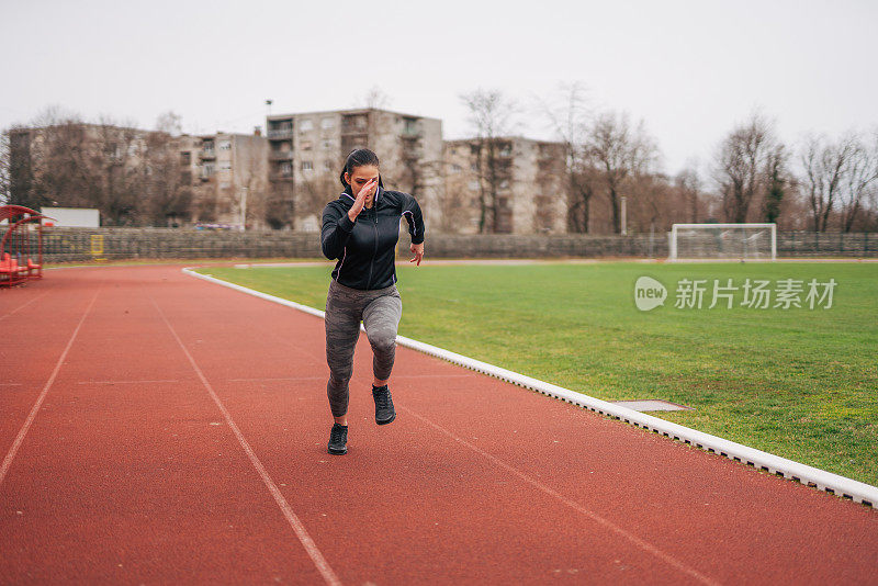 A young athlete is training. She runs on the athletics track.